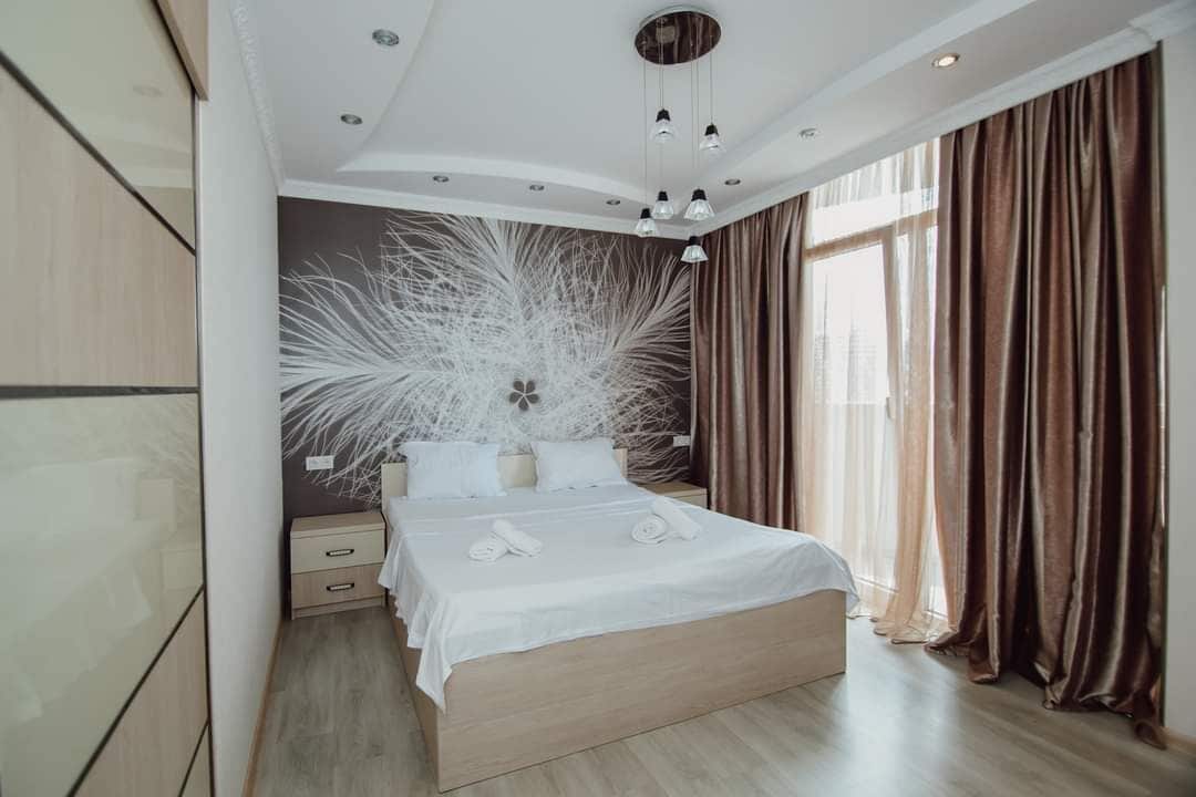 Ein modernes Schlafzimmer mit einem großen Bett, einem Nachttisch und einer Wanddekoration.