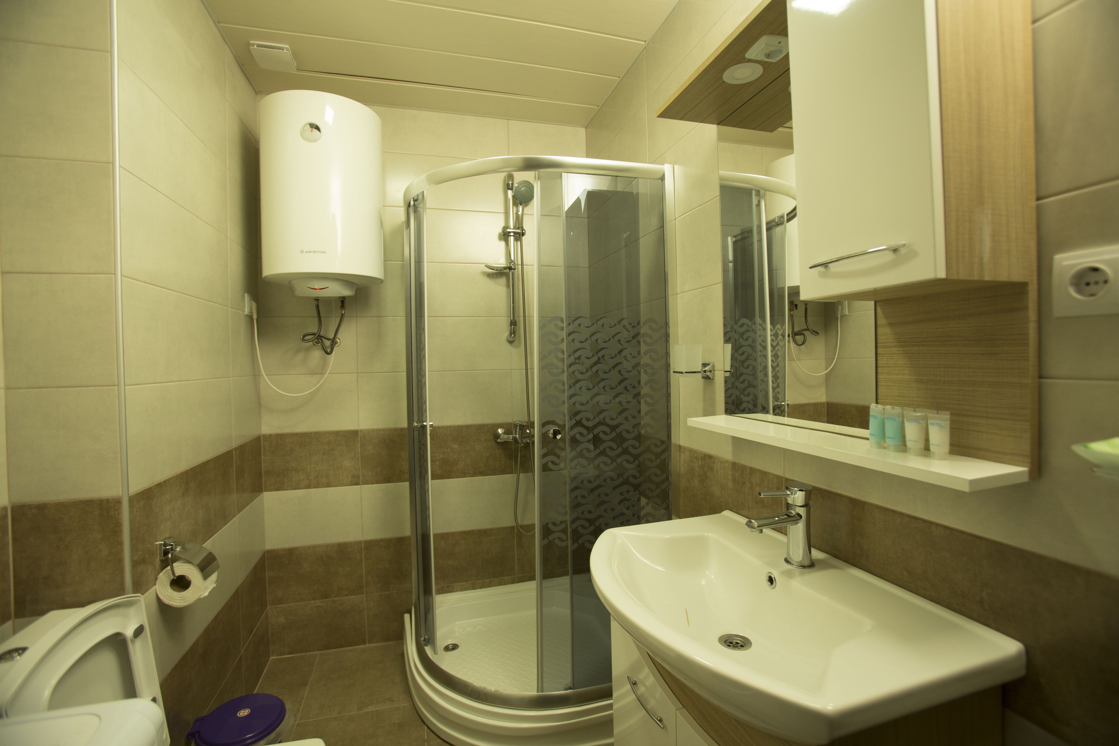 A bathroom with a shower, toilet, sink, and a mirror.