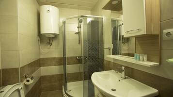 A bathroom with a shower, toilet, sink, and a mirror.