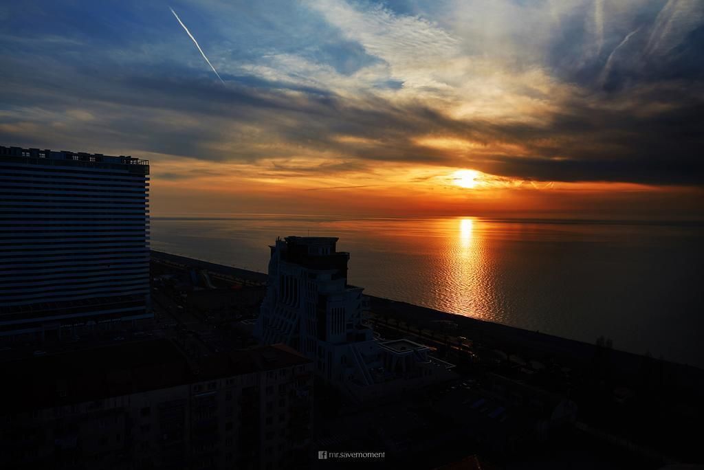 A sunset over a body of water with buildings in the foreground.