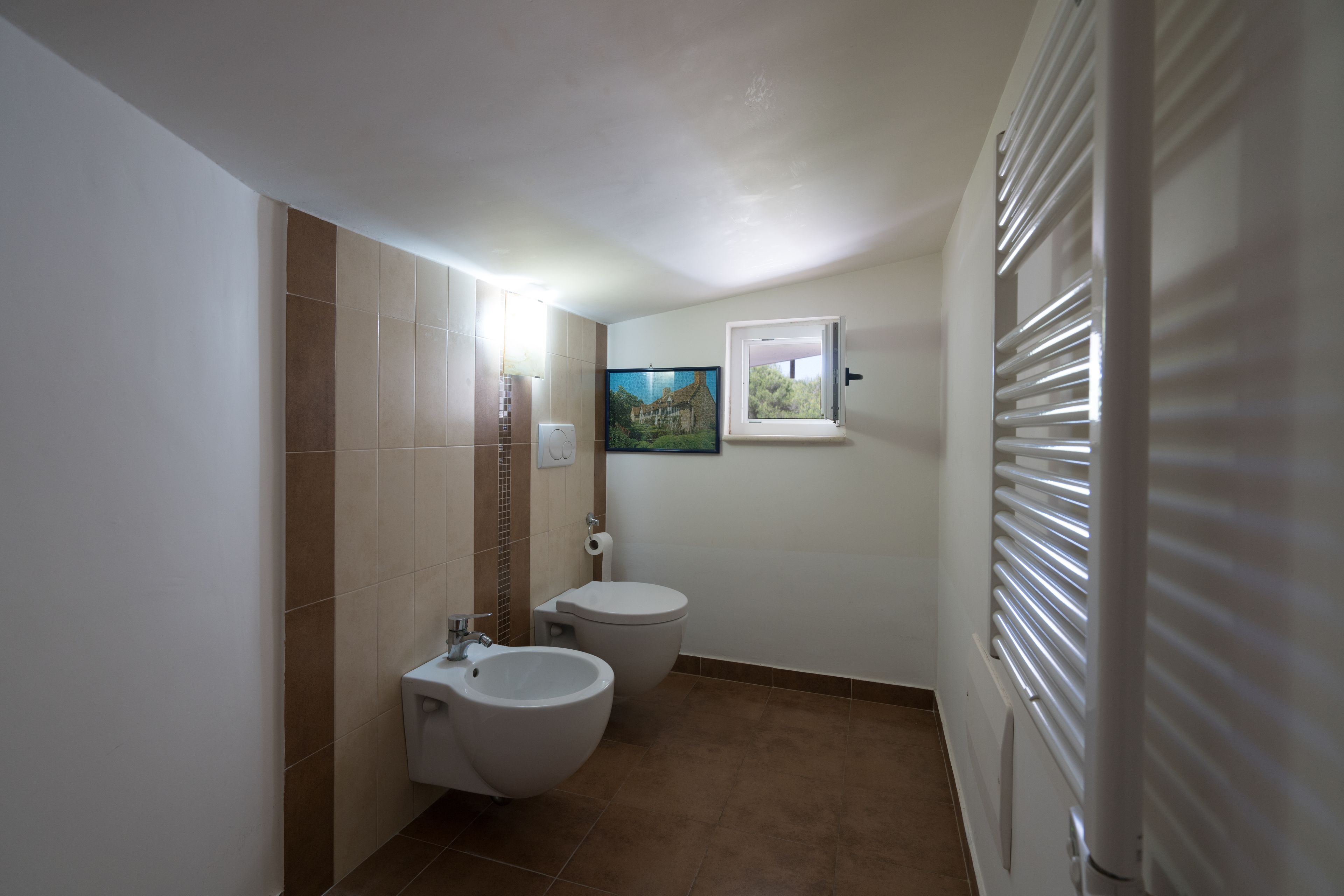 Ein Badezimmer mit Toilette, Bidet und einem kleinen Fenster.