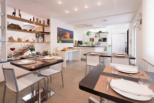 Una cocina moderna con zona de comedor, que presenta una isla central, estanterías empotradas y un cuadro grande.