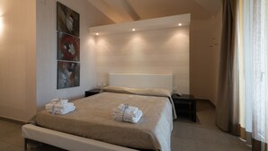 A modern hotel room with a large bed, a bedside table, and a wall-mounted artwork.