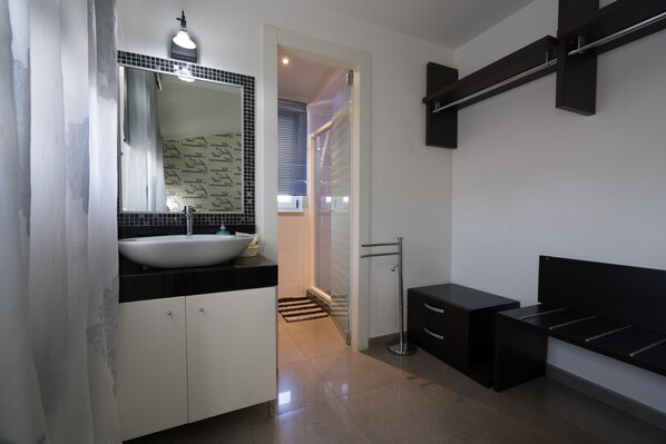 A modern bathroom with a large sink, mirror, and black cabinetry.