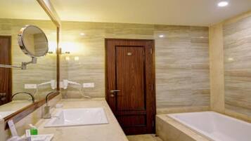 A bathroom with two sinks, a mirror, a wooden door, and a bathtub.