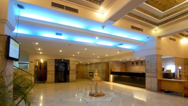 A spacious lobby with a marble floor, a reception desk, and a statue in the center. - Hotel Chanakya (Patna)