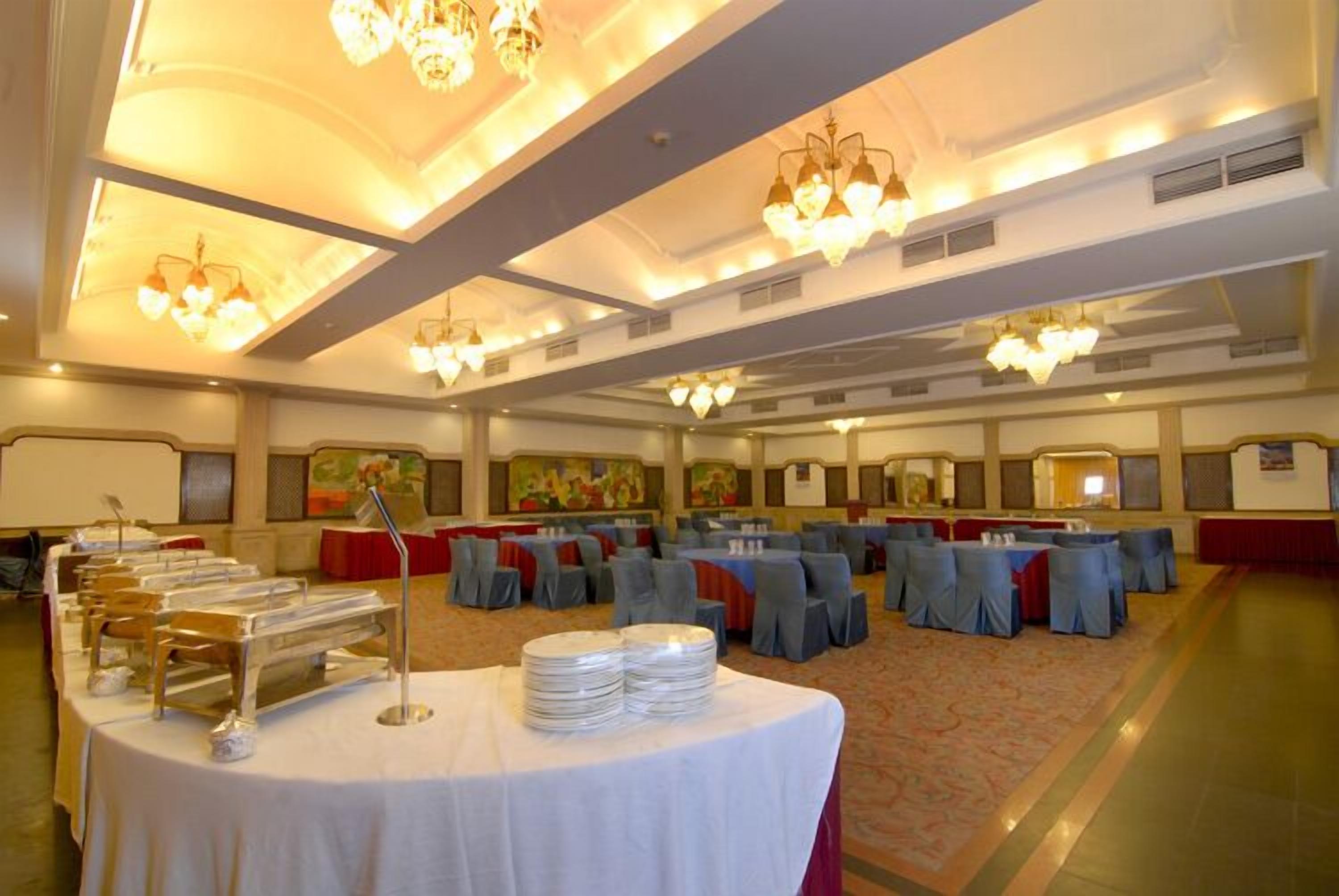 A banquet hall with round tables, chairs, and a buffet setup.