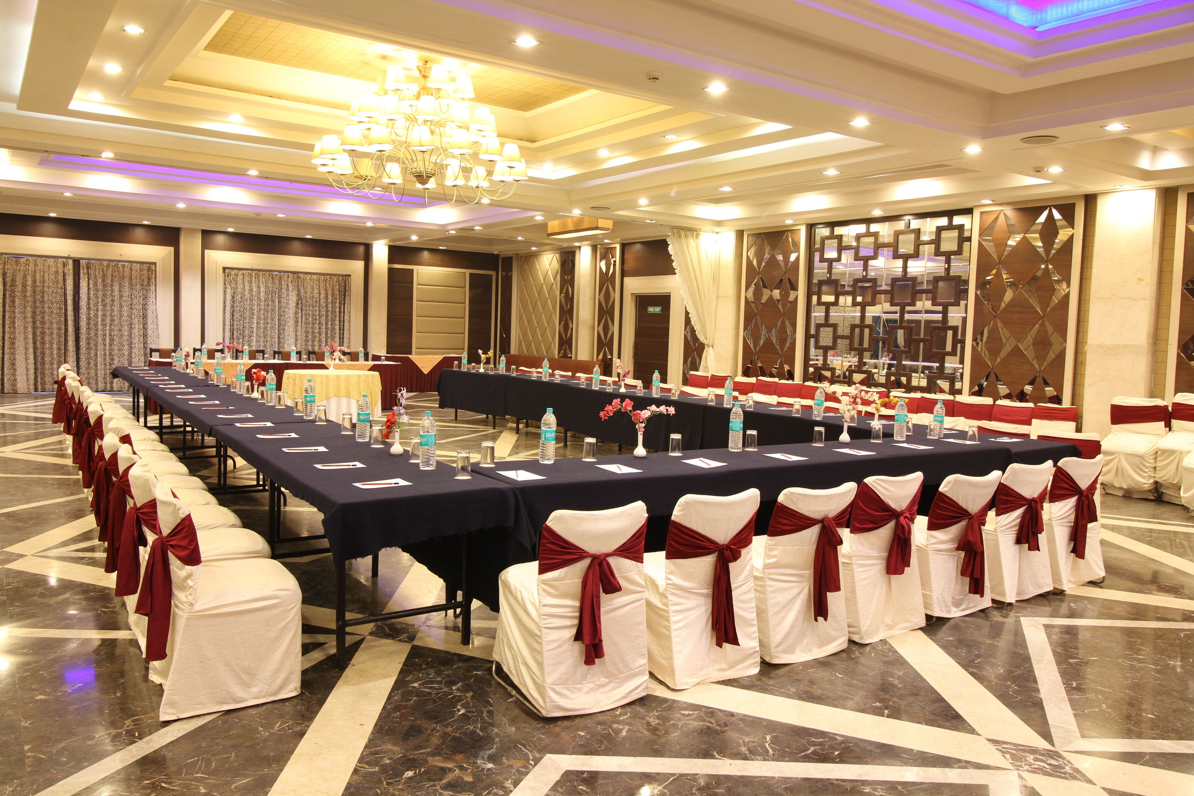 A conference room with a long table, chairs with red sashes, and a chandelier.