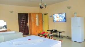 Una habitación de hotel con una cama, un escritorio con computadora, televisor y refrigerador.