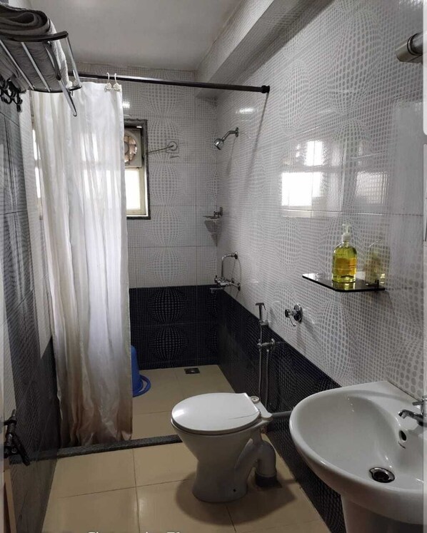 A bathroom with a toilet, sink, shower, and a towel rack.