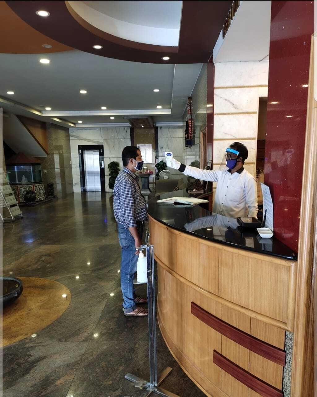 A hotel reception area with a marble floor, a reception desk, and a glass partition.