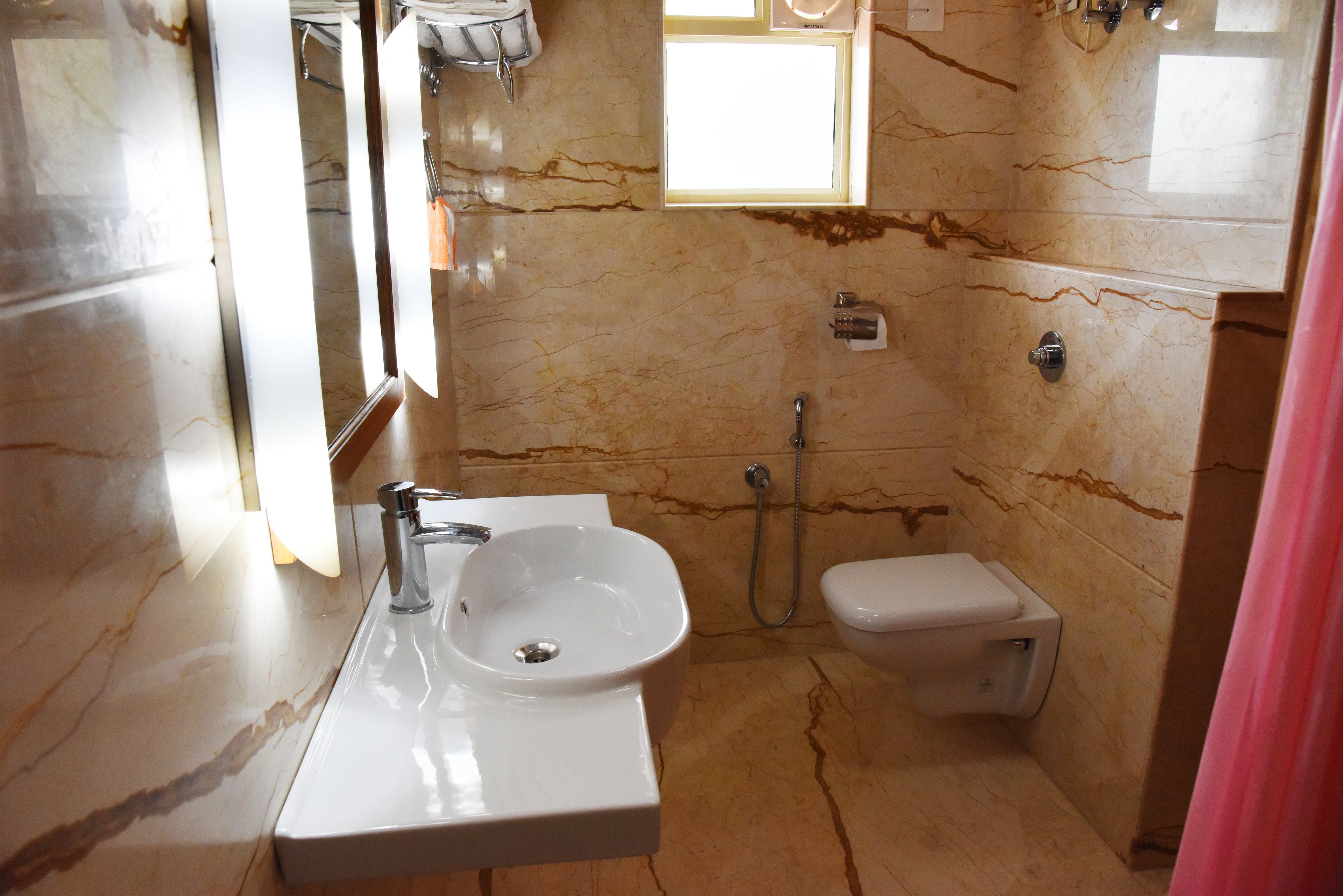 A bathroom with a marble sink, a toilet, and a shower.
