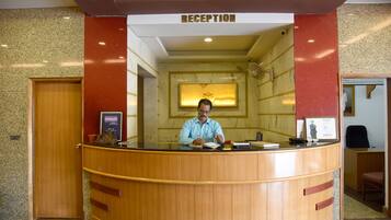 Un mostrador de recepción con detalles de madera, un cartel encima que dice "RECEPTION" y una foto enmarcada en la pared detrás del mostrador.