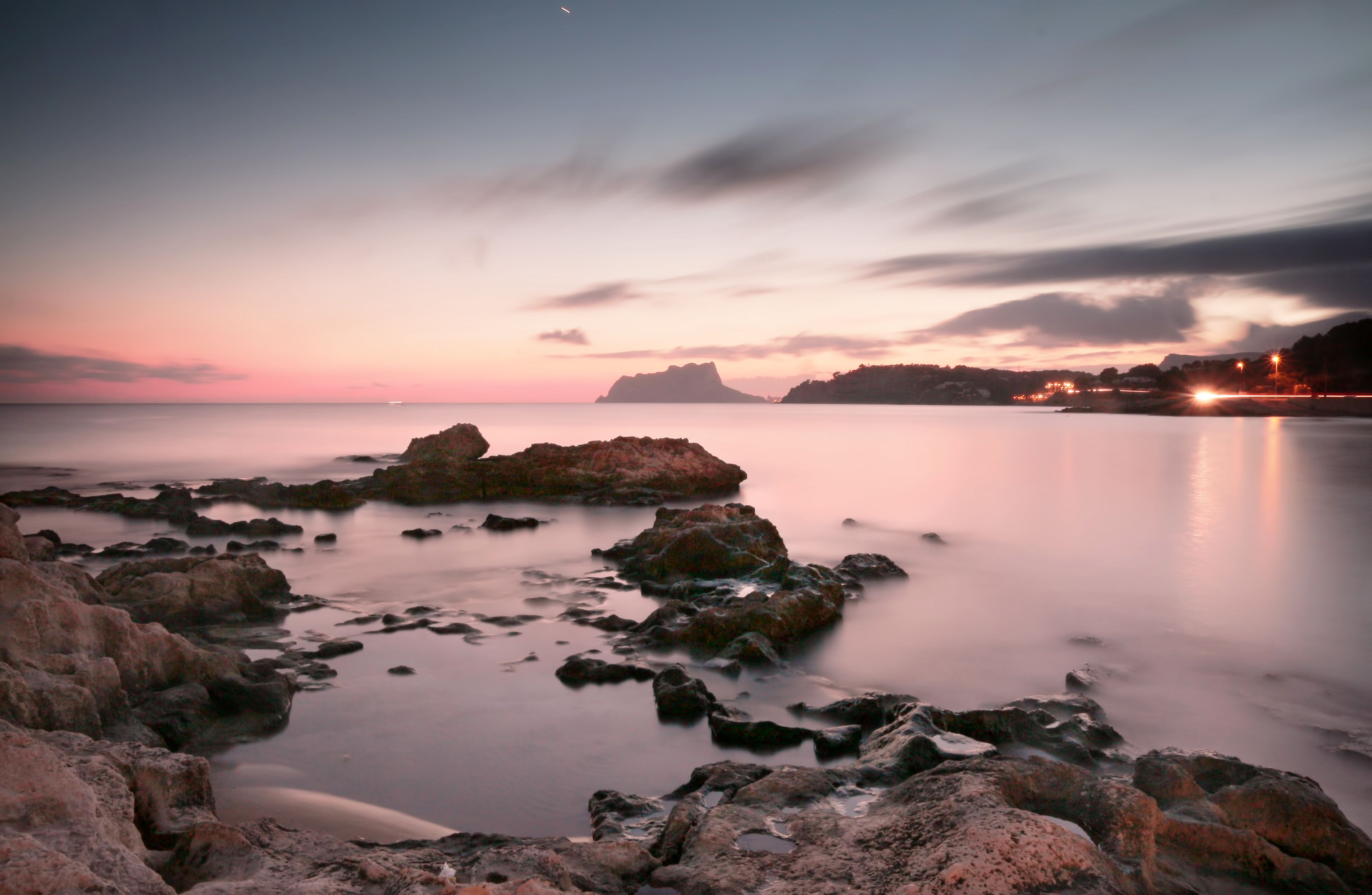 A coastal landscape with rocky formations and calm water.