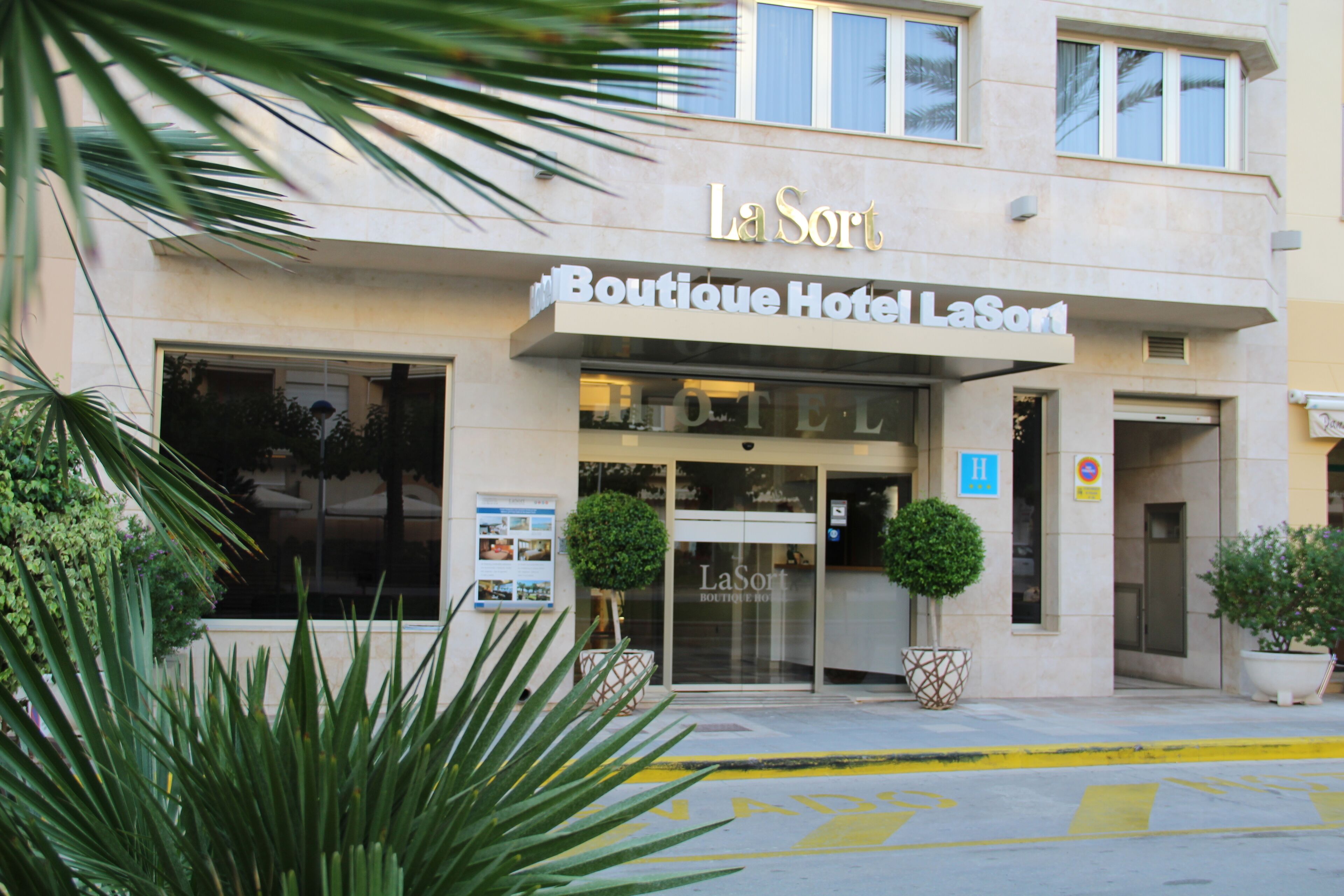 L’entrée du Boutique Hotel LaSort est clairement indiquée par un panneau, elle est accessible aux personnes en fauteuil roulant et agrémentée de plantes en pot.
