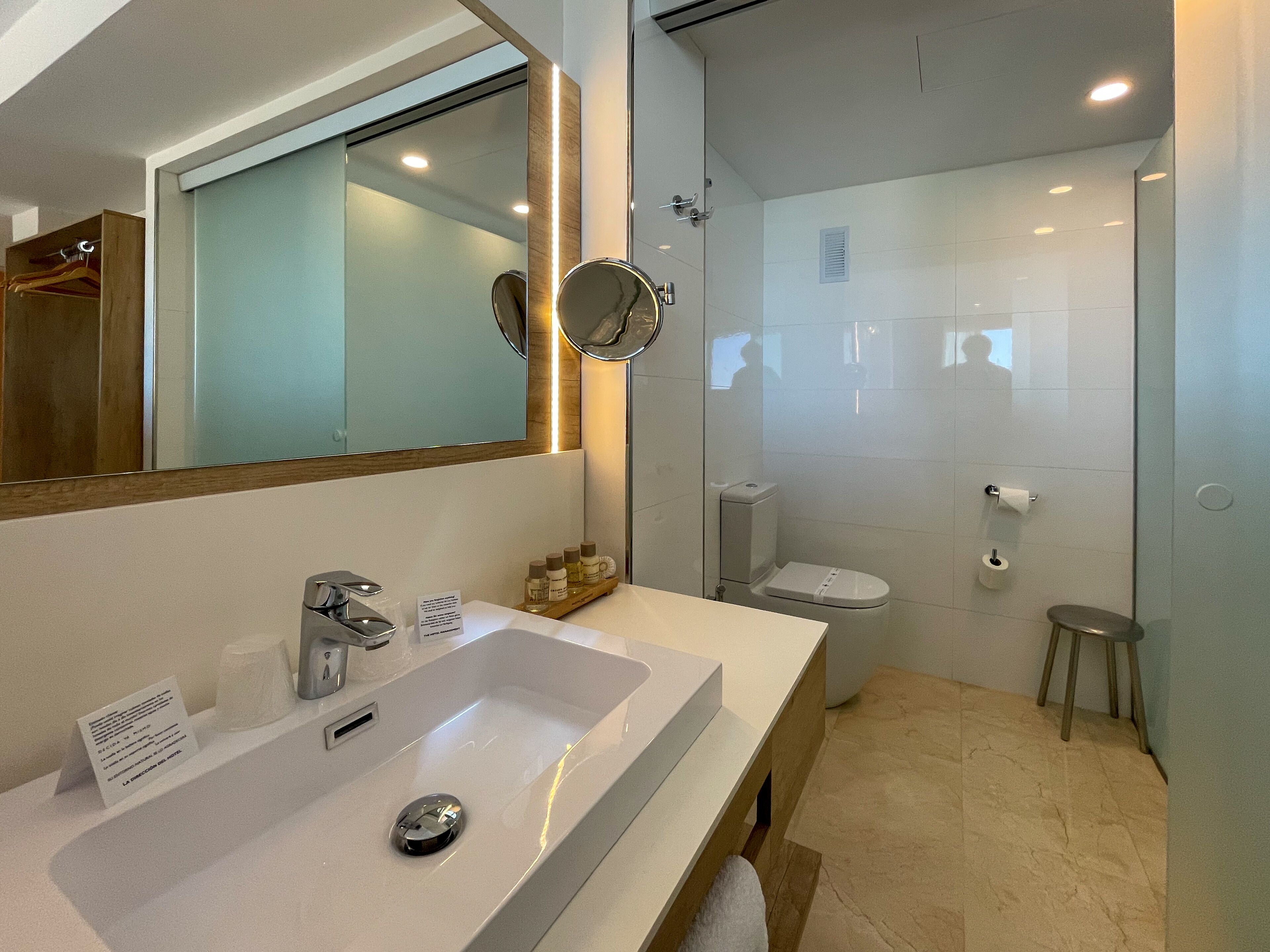A modern bathroom with a large sink, mirror, and shower.