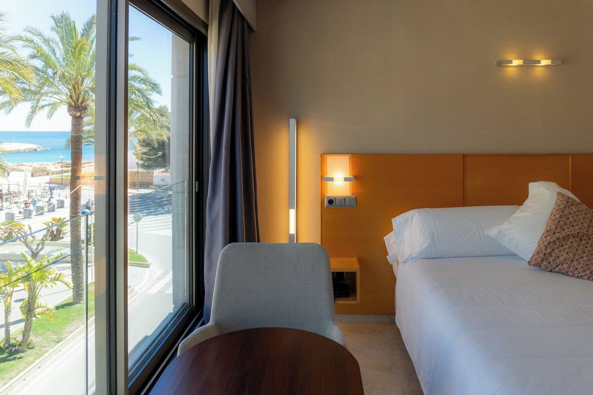 Une chambre d’hôtel avec un lit, une chaise, une table et une vue sur la plage.