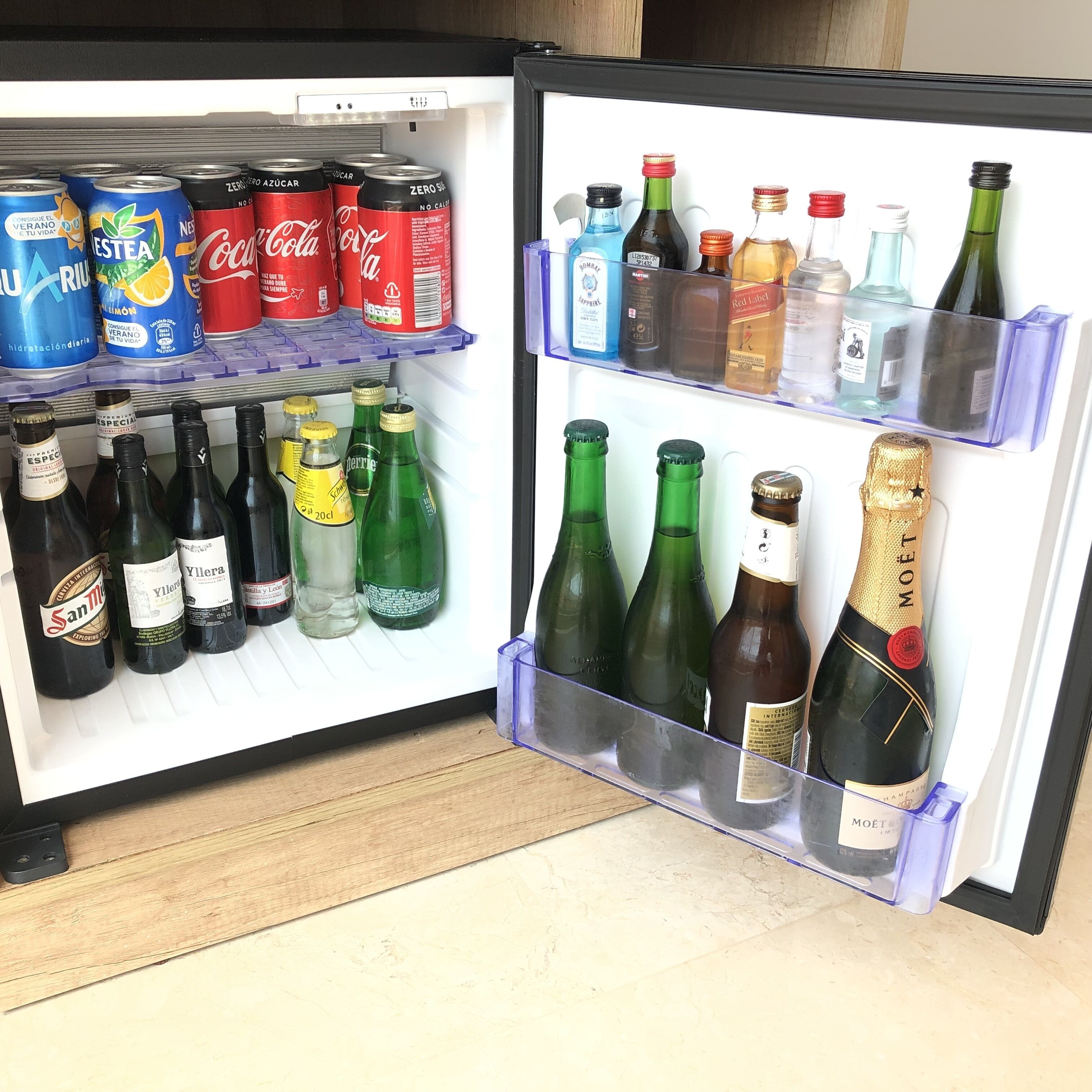 Un réfrigérateur rempli de diverses boissons, notamment des sodas, des vins et du champagne.