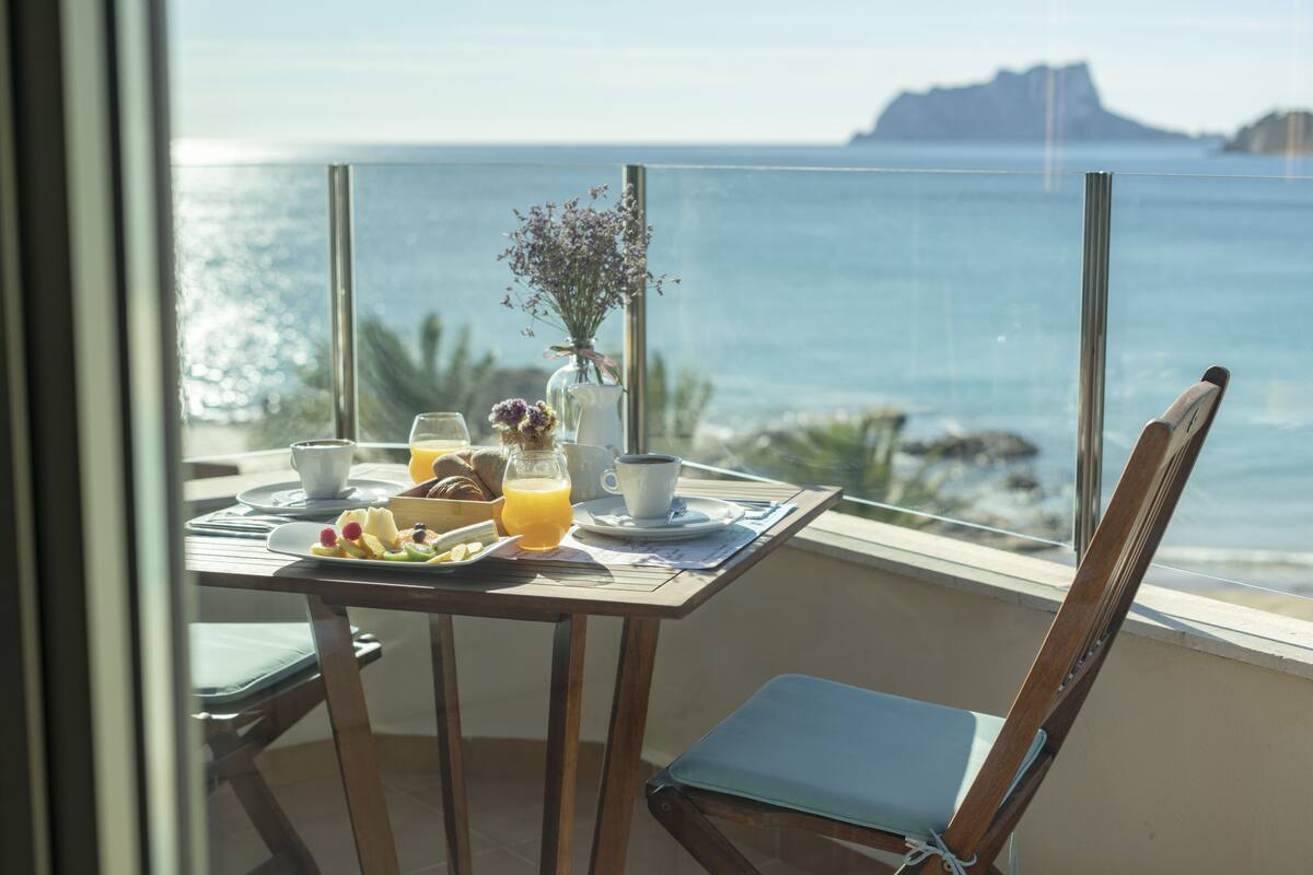 Un balcon avec une table préparée pour le petit-déjeuner, donnant sur la mer.