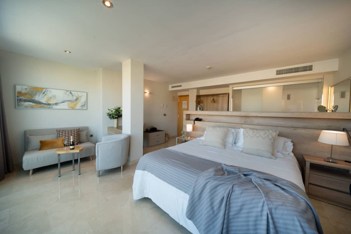 Une chambre d’hôtel moderne avec un grand lit, un canapé, une petite table et une table de chevet.