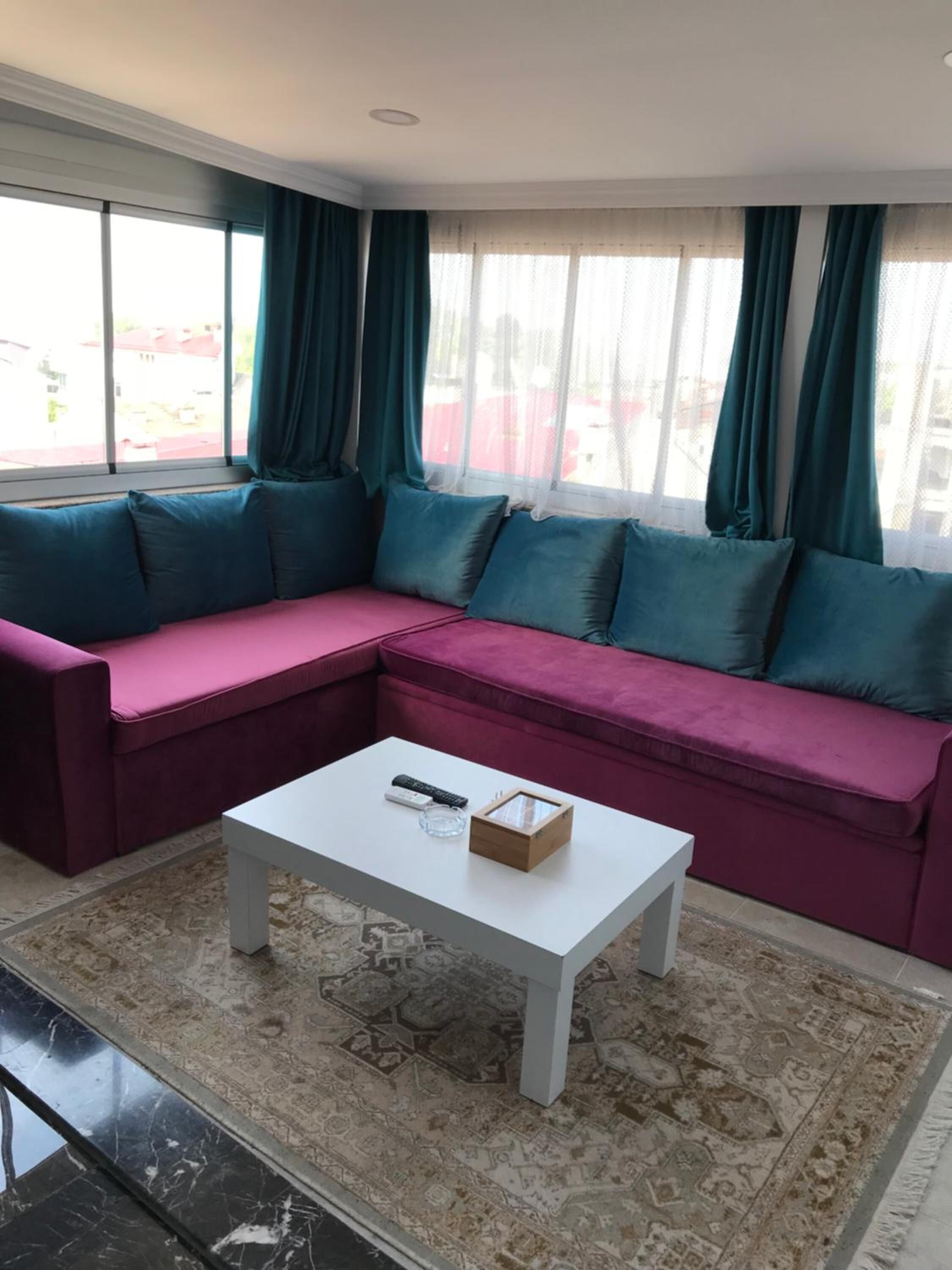 Una sala moderna con un sofá seccional rosa, una mesa de centro blanca y una alfombra estampada.