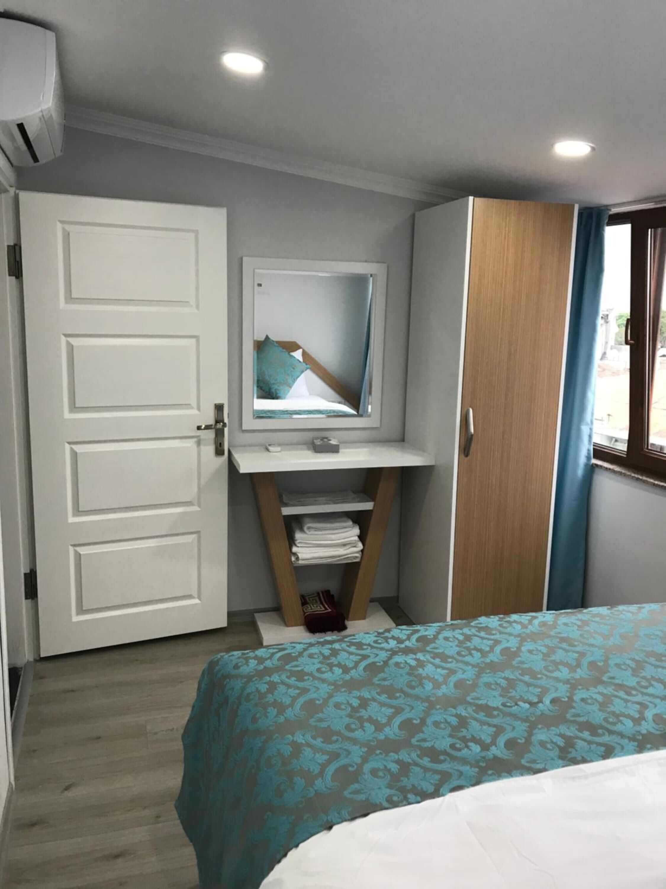 Una habitación de hotel con cama, escritorio con espejo, armario y puerta.