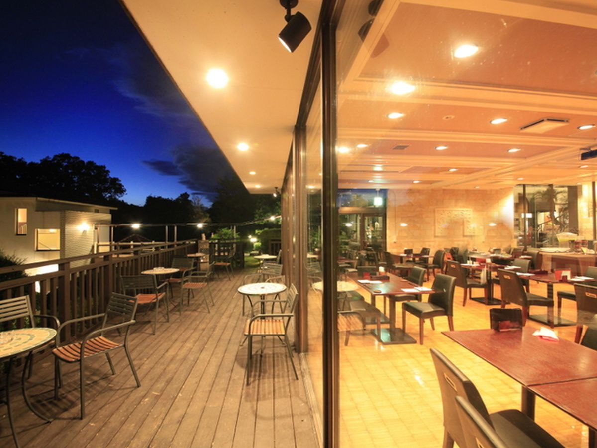 An outdoor dining area with tables and chairs, a wooden deck, and a view of the sky.