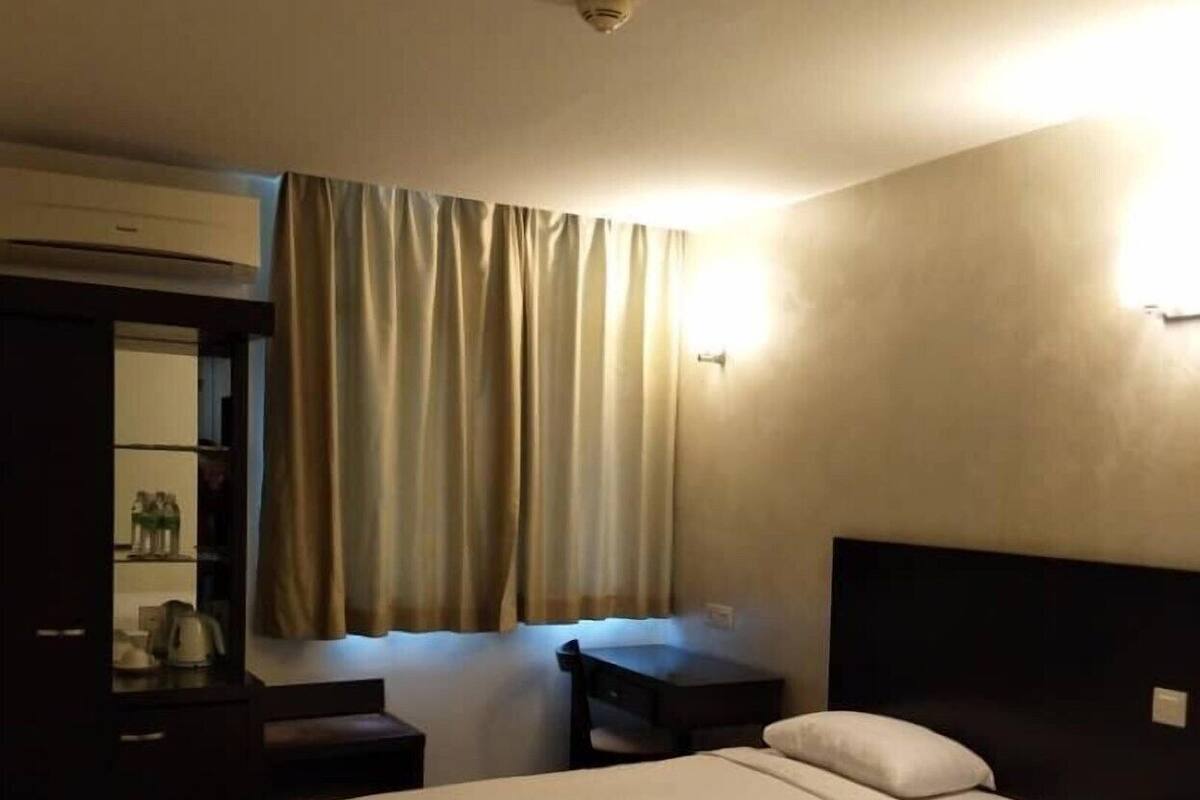 A hotel room with two beds, a desk, a chair, a wardrobe, and a curtain.
