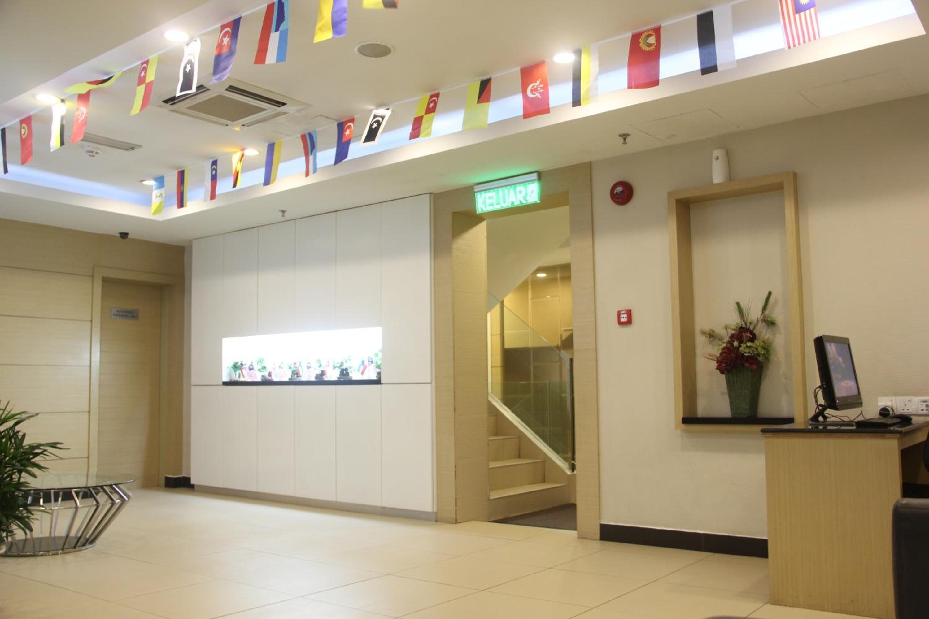 A reception area with a glass desk, a staircase, and a wall-mounted sign.