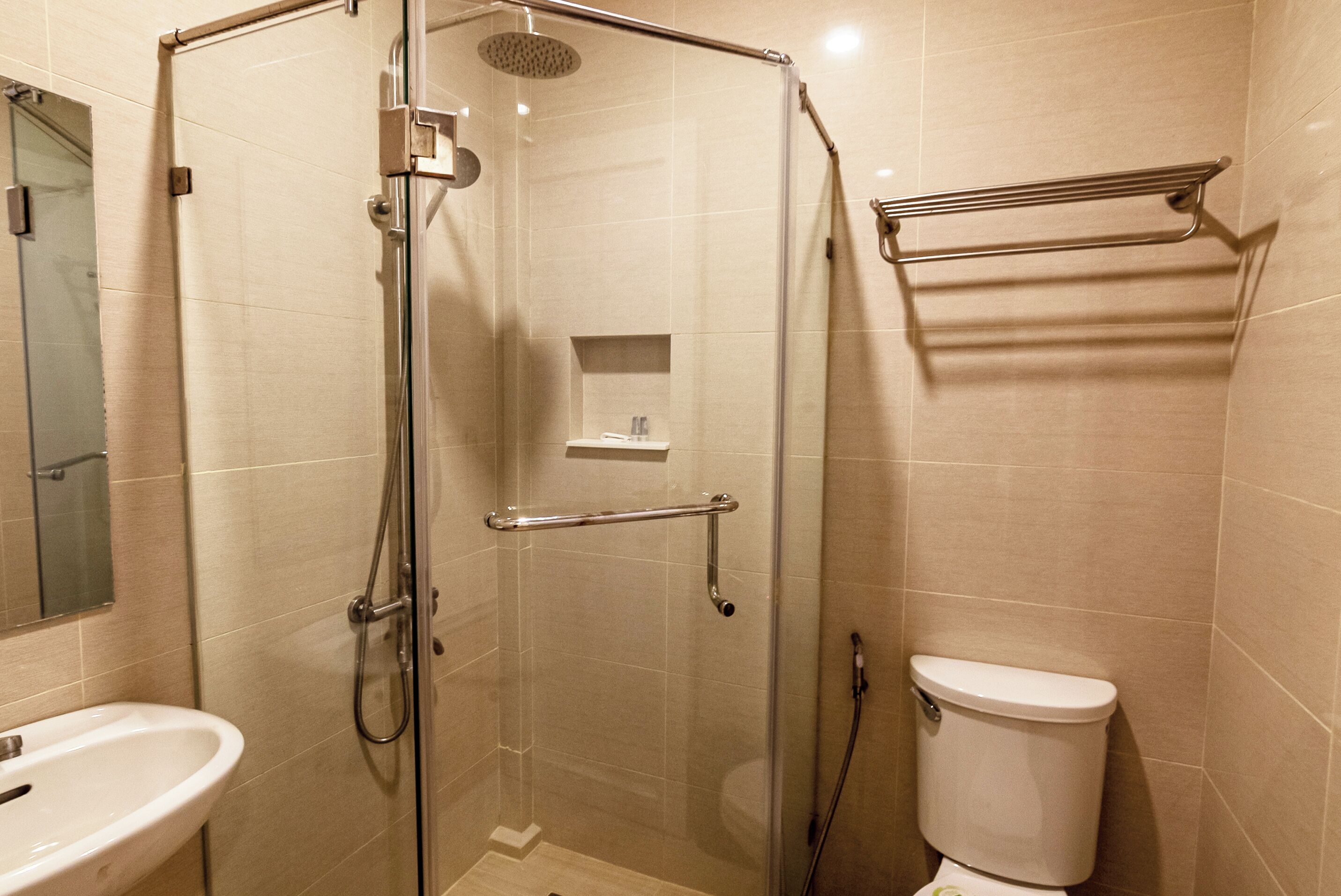 Un baño moderno con ducha de vidrio, lavamanos blanco y un inodoro.