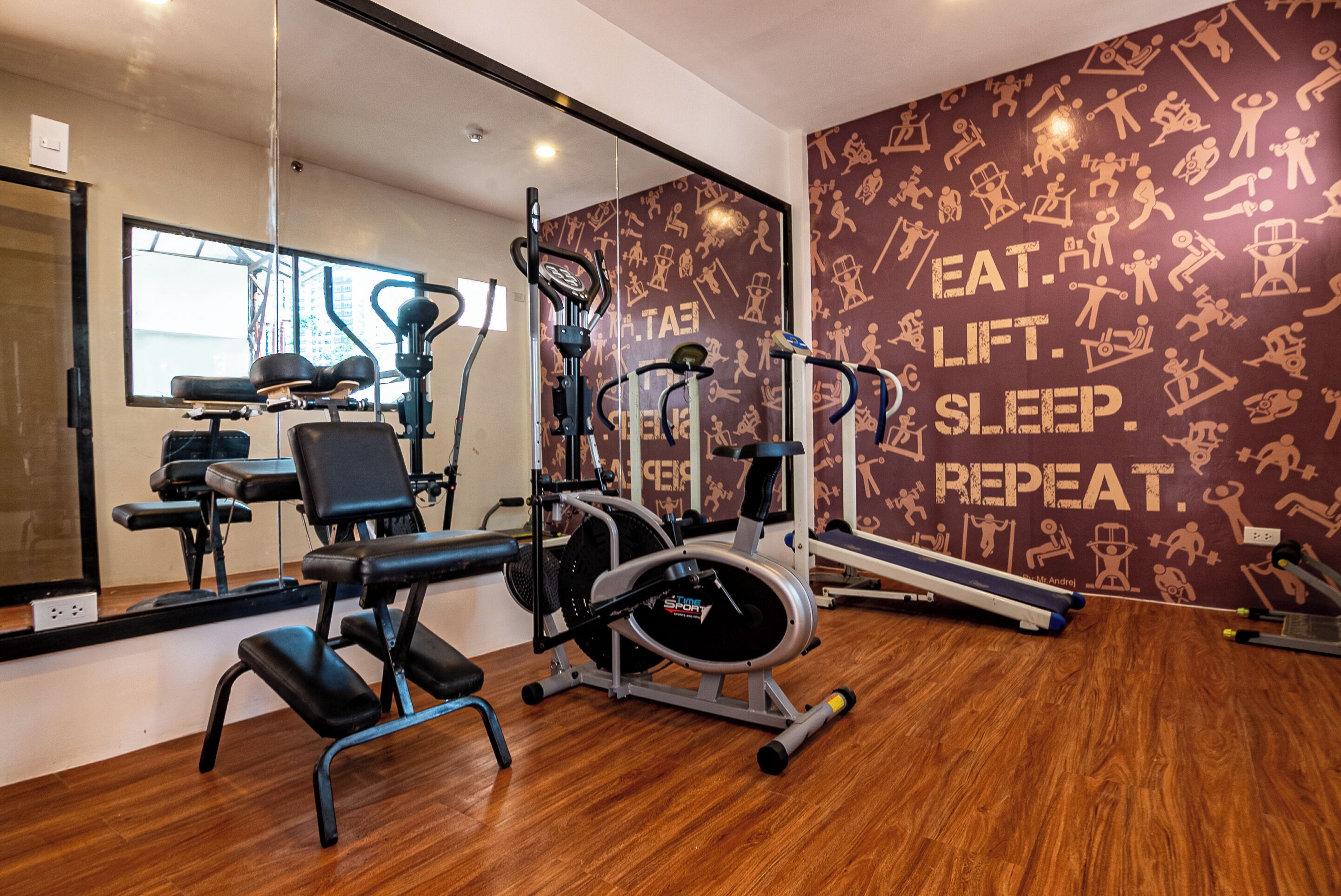 A gym with exercise equipment, a mirrored wall, and motivational posters.