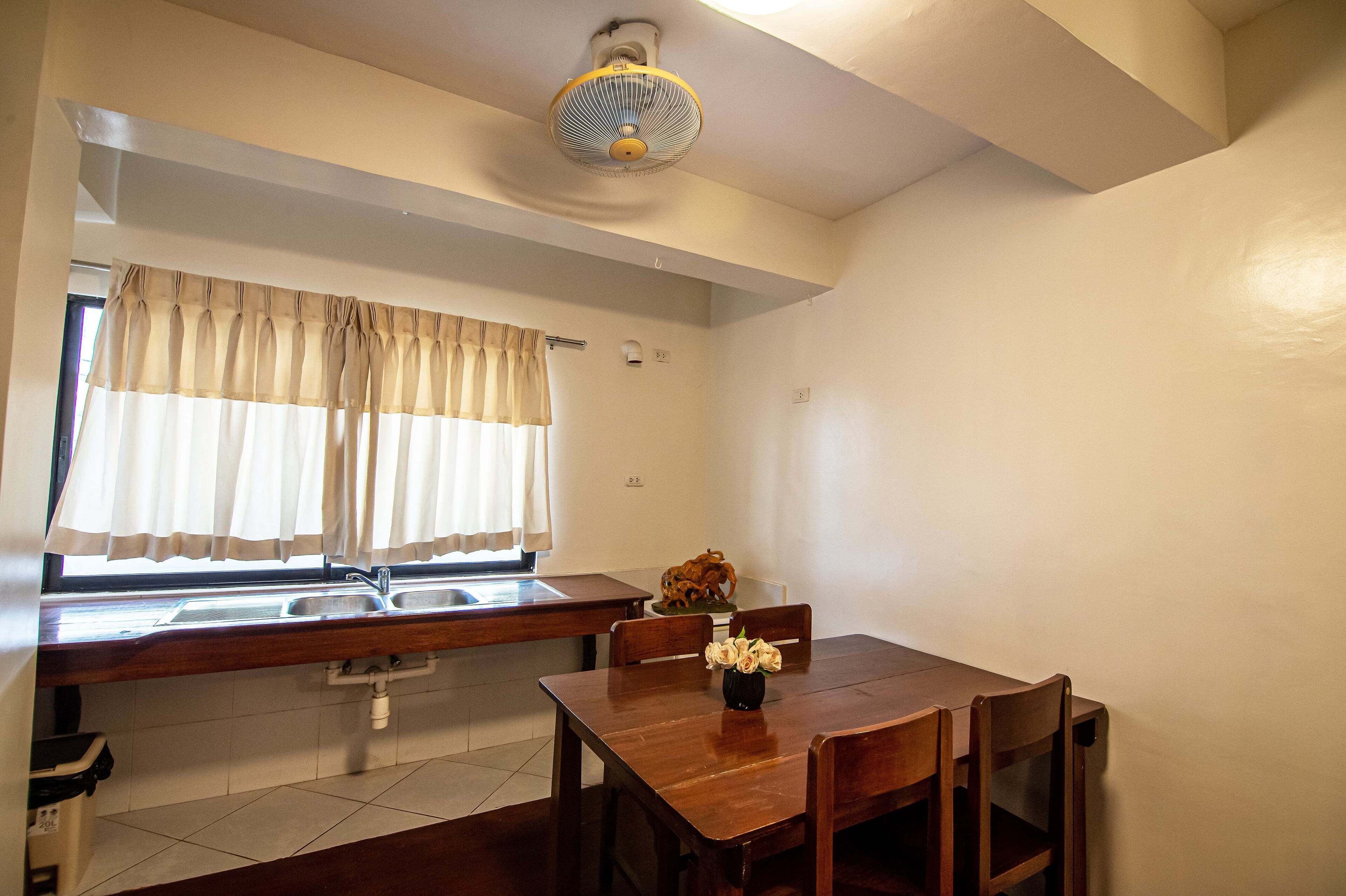 Una cocina con ventana, pileta y comedor con sillas y mesa.