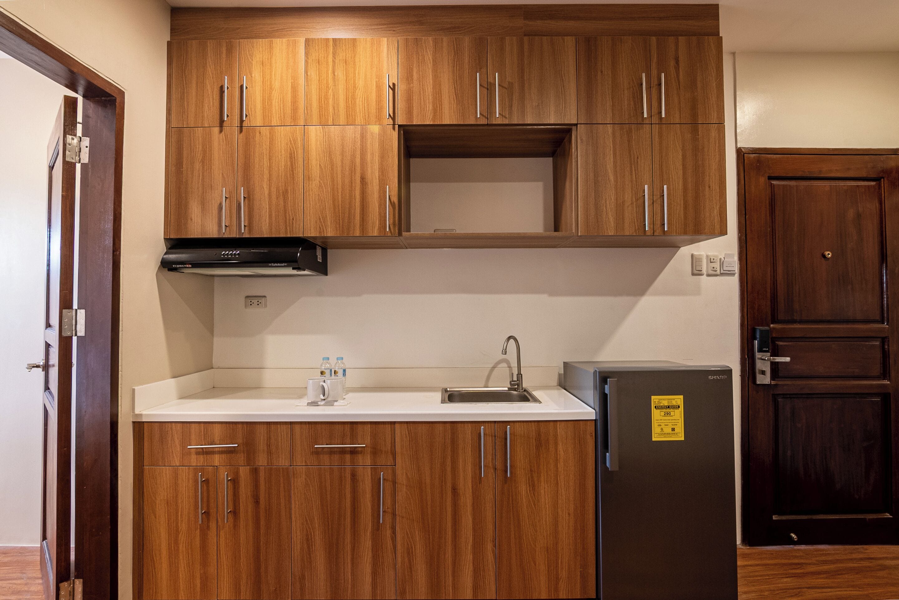 A kitchen with wooden cabinets, a stainless steel sink, and a refrigerator.