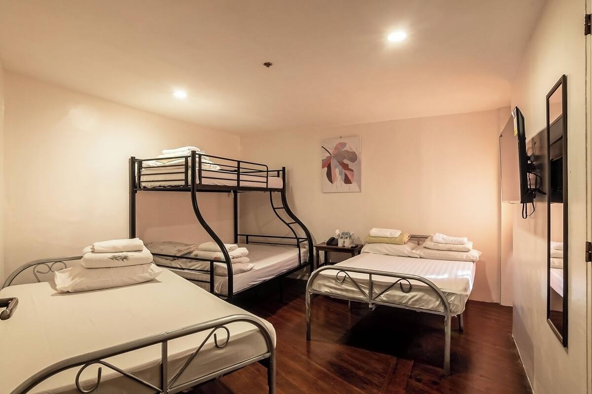 A room with two bunk beds, a single bed, and a small table with a chair.