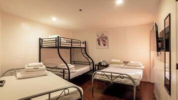 Una habitación con dos literas, una cama individual y una pequeña mesa con una silla.