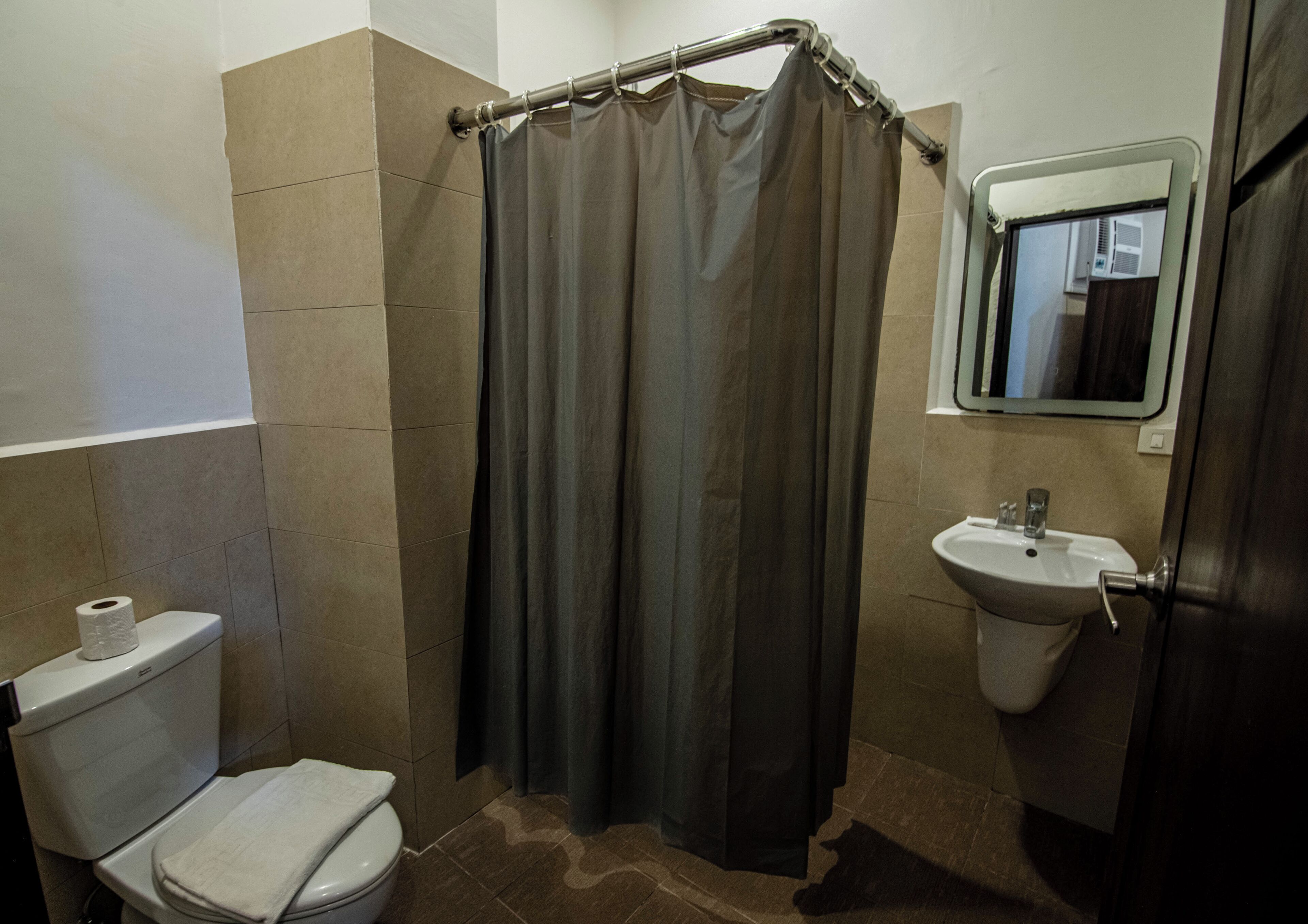 Un baño con inodoro, lavamanos y cortina de ducha.