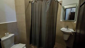 Un baño con inodoro, lavamanos y cortina de ducha.
