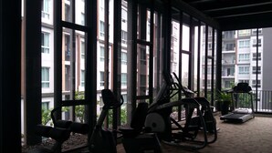 A gym with exercise equipment, large windows, and a view of a building. - dcondo mine by BP (Kathu)