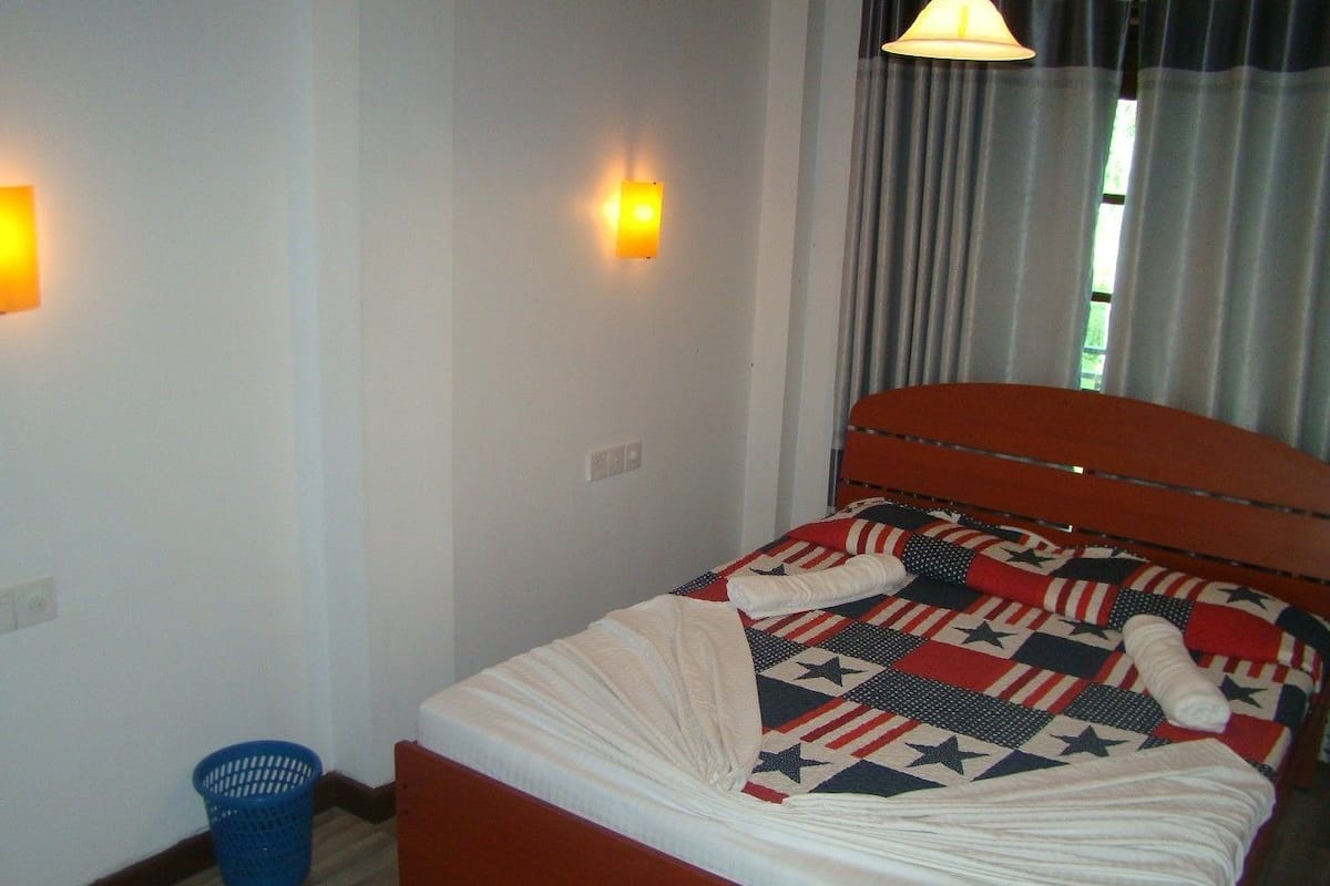 Ein Bett mit einer Steudecke, einem blauen Korb und einer Wandleuchte.