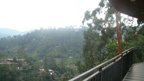 Un balcón con vistas a un valle verde y casas dispersas.