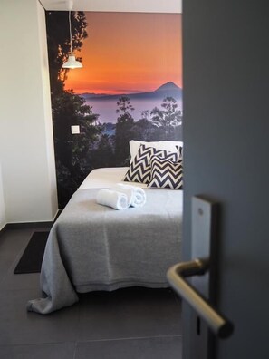 Una camera da letto con un letto, vista sul tramonto e una porta con maniglia.