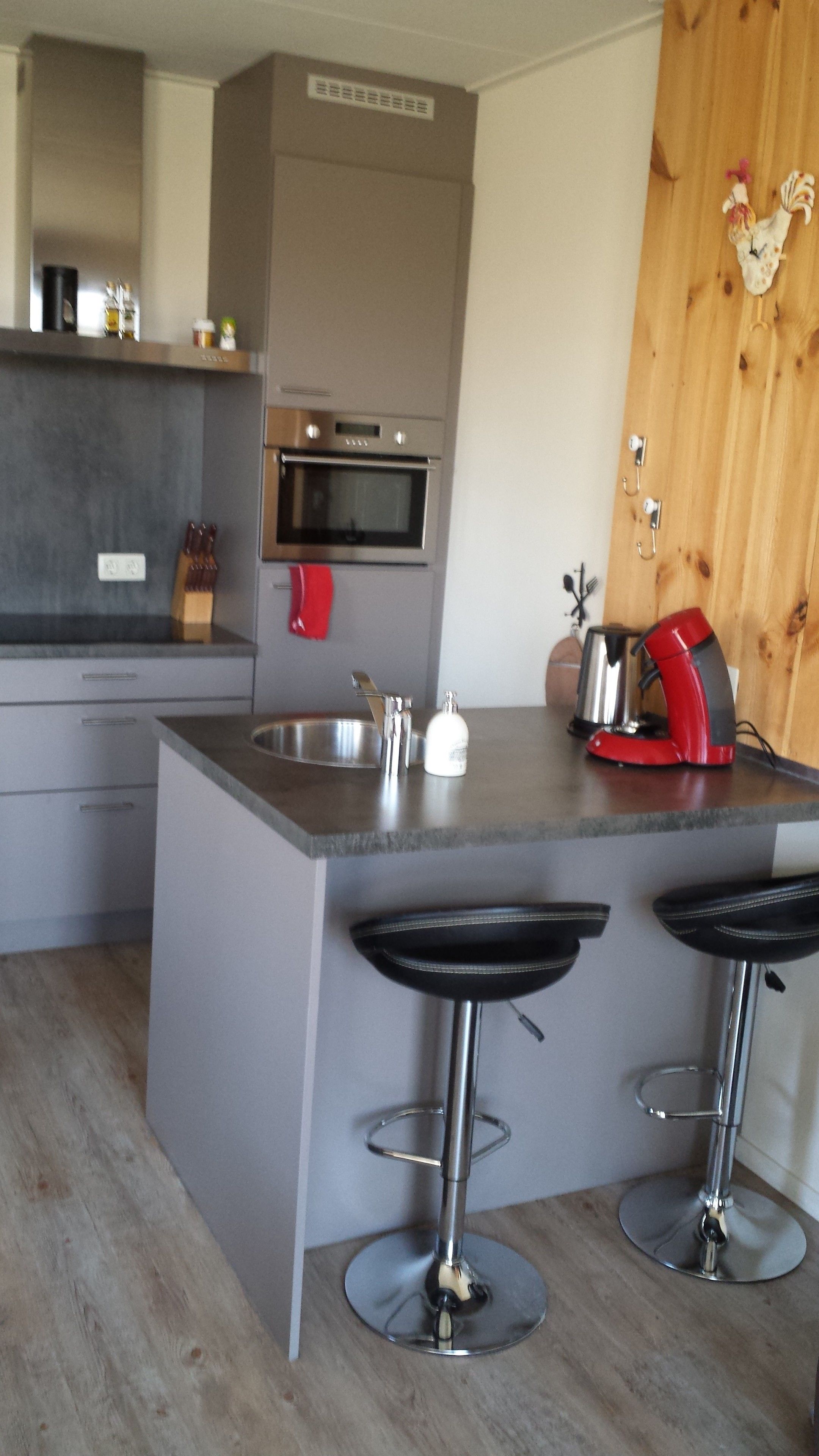 A modern kitchen with a central island, stainless steel appliances, and two bar stools.