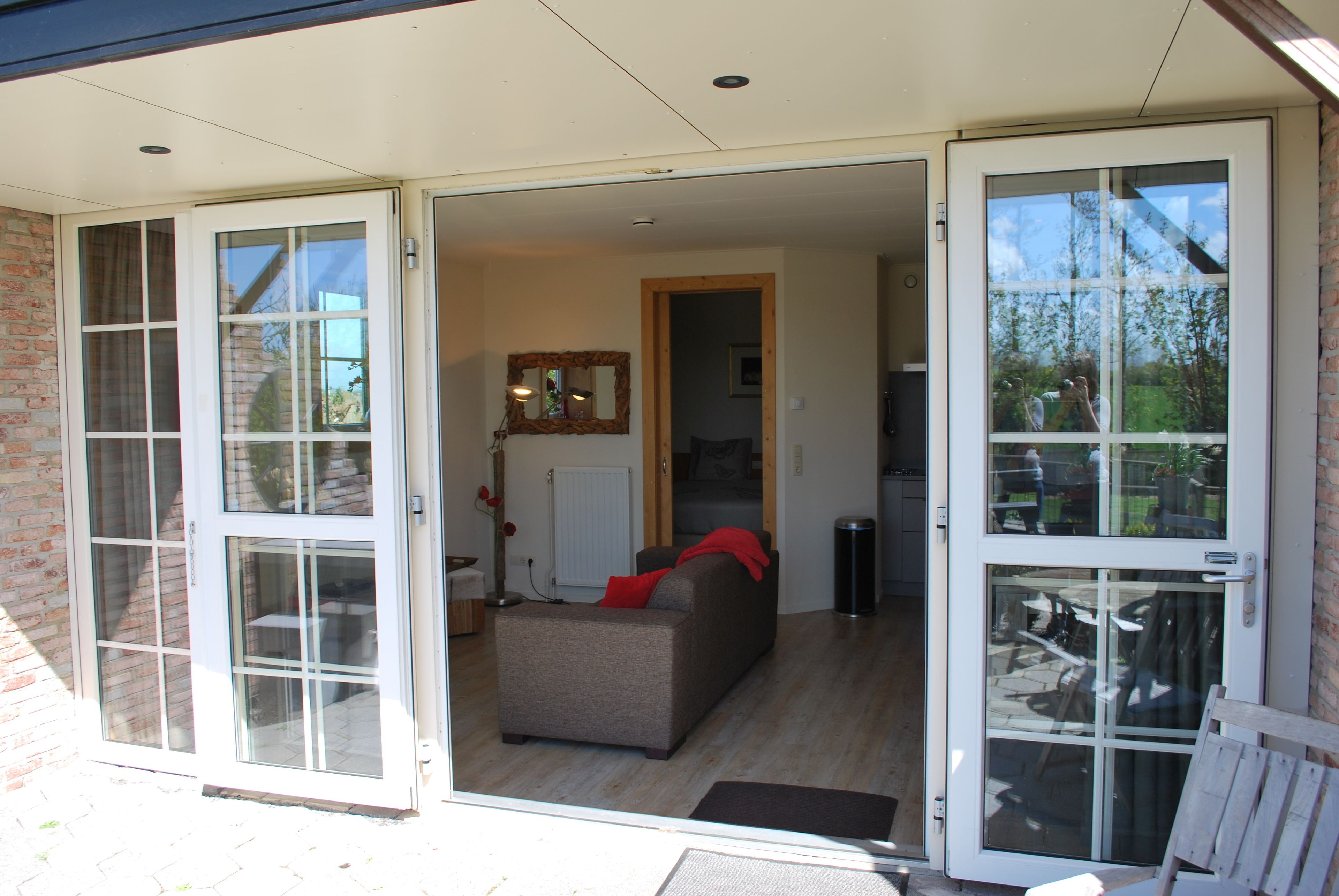 A living room with a sofa and a coffee table, a dining area with chairs, and a kitchen area with a refrigerator and sink.