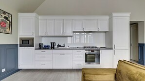 A modern kitchen with white cabinets, a microwave, stove, and a sofa in the foreground. - Scandi Love BestSeller by Lion Apartments Sopot (Sopot)