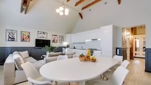 A modern kitchen with white cabinets, a dining table with chairs, and a ceiling with exposed beams. - Scandi Love BestSeller by Lion Apartments Sopot (Sopot)