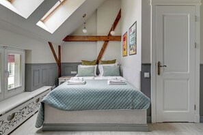 A bedroom with a bed, skylight, wooden beams, a bench, and a door. - Lion Apartments - Scandi Love (Sopot)