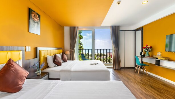 Habitación de hotel con dos camas, un balcón, un escritorio y un televisor.