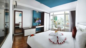 Un hotel moderno con una cama grande, un televisor montado en la pared, un escritorio con una silla y un balcón con vistas a la ciudad.