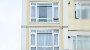 Un edificio de varios pisos con entrada a nivel de calle, un letrero y una escalera que lleva a la entrada.