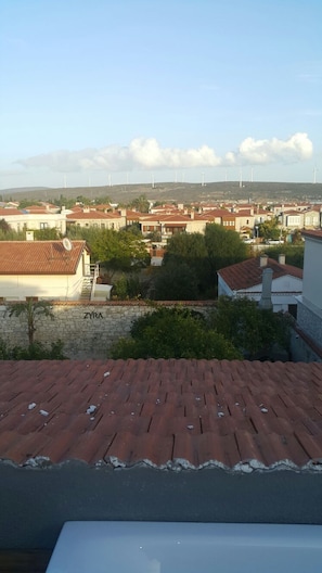 A residential area with houses, a stone wall with 'ZYRA' written on it, and wind turbines in the distance. - Alacati The Hotel (Cesme)